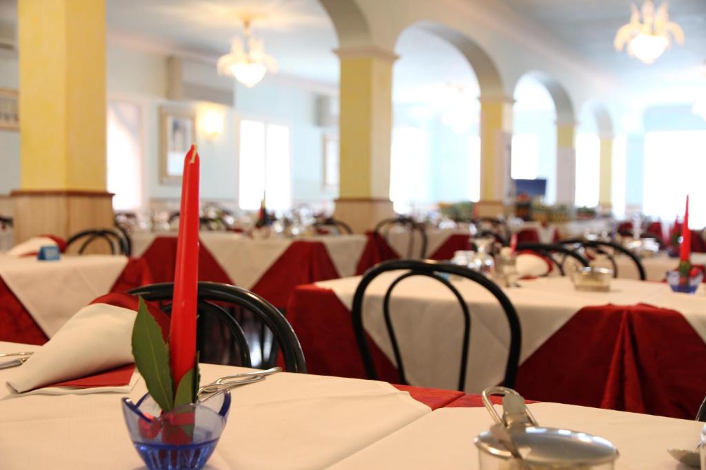a dining room with tables and chairs with red candles at Hotel Maxim in Caorle