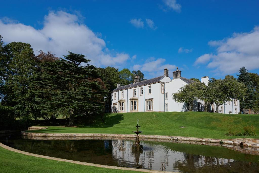 a large white house with a pond in front of it at Farlam Hall Hotel & Restaurant in Brampton