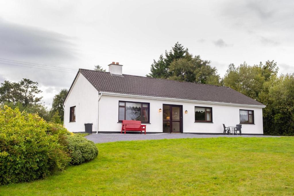 a white house with a red bench in a yard at Cottage 431 - Oughterard in Oughterard