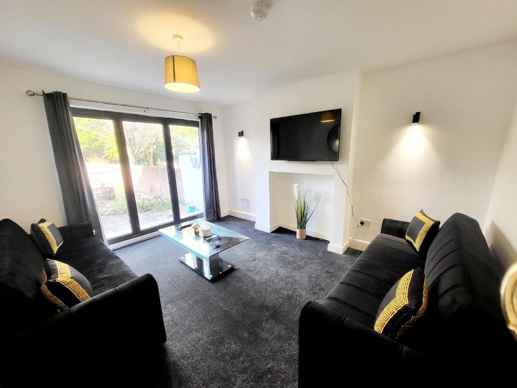 a living room with two black couches and a tv at Unique and beautiful property in a quiet location. in Nottingham