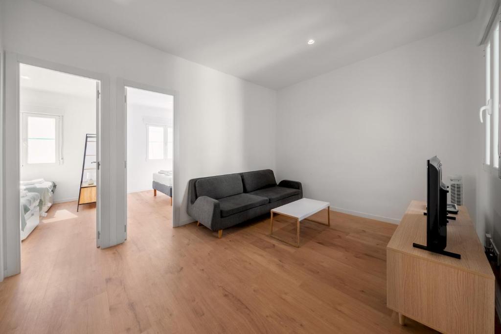 uma sala de estar com um sofá preto e uma televisão em 2 bedrooms 1 bathroom furnished - Delicias - bright - MintyStay em Madri