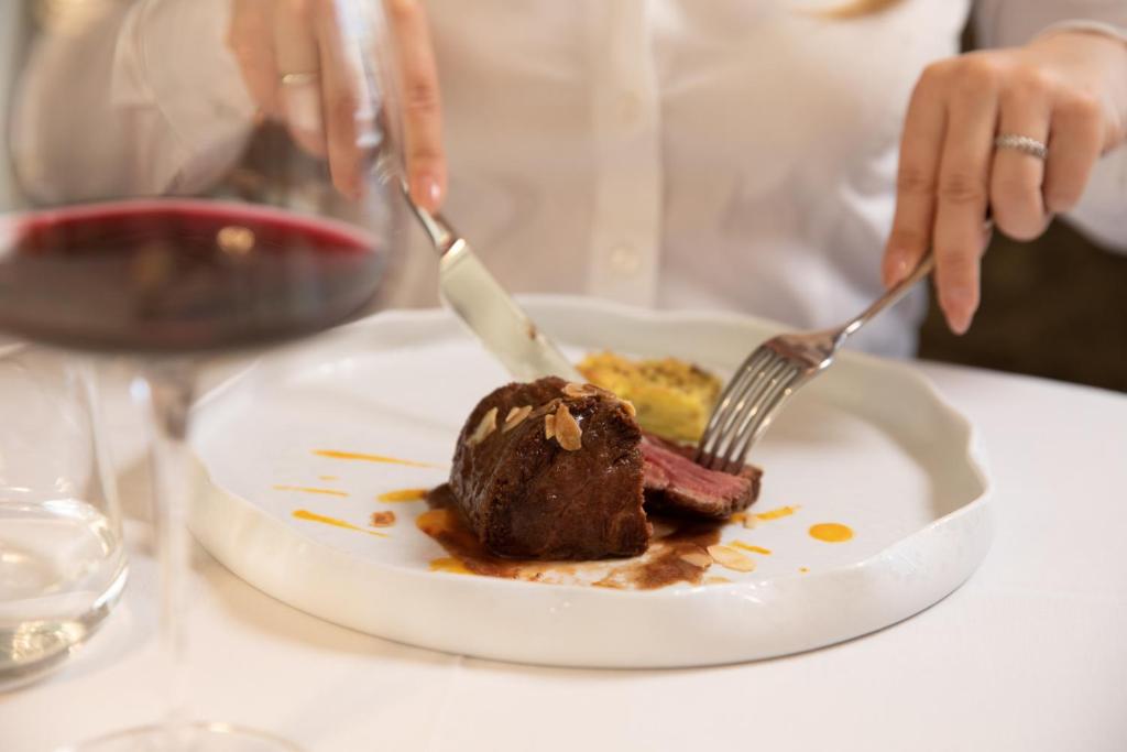a person eating a dessert on a plate with two forks at Hotel Villa Pascucci in Durrës