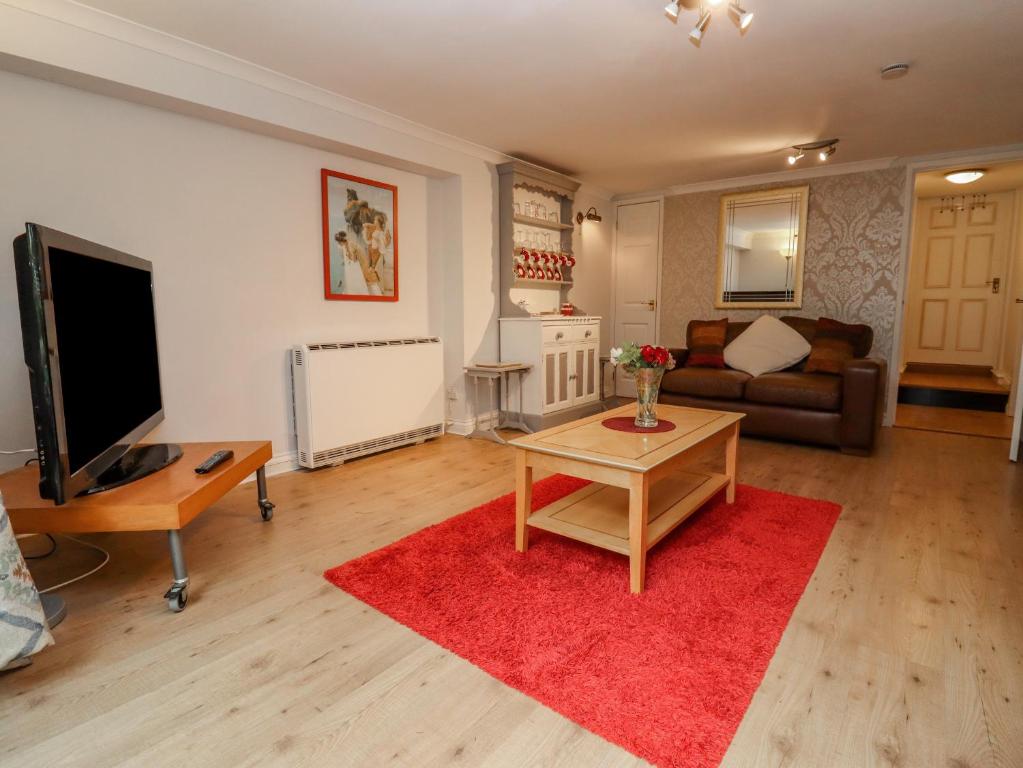 uma sala de estar com uma televisão e um tapete vermelho em Tinkletod em Clevedon