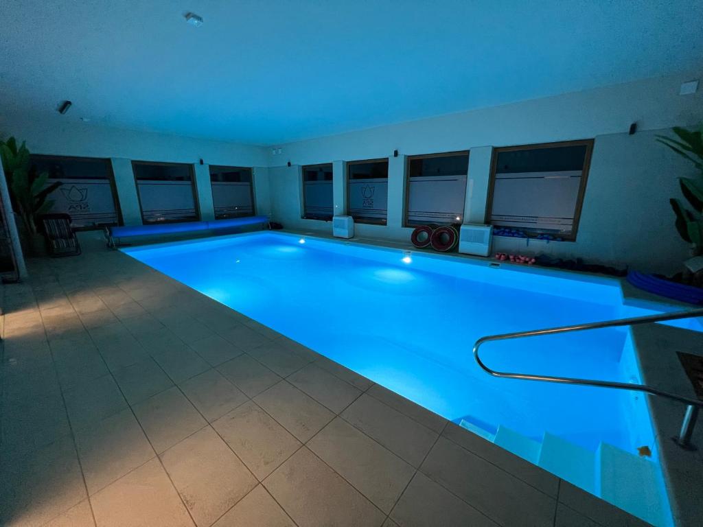 duży basen z niebieskim oświetleniem w pokoju w obiekcie Medical Spa Kwiatowa w mieście Łęczyca