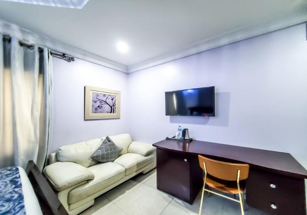 a hotel room with a couch and a desk and a tv at Medallion Hotels in Lagos