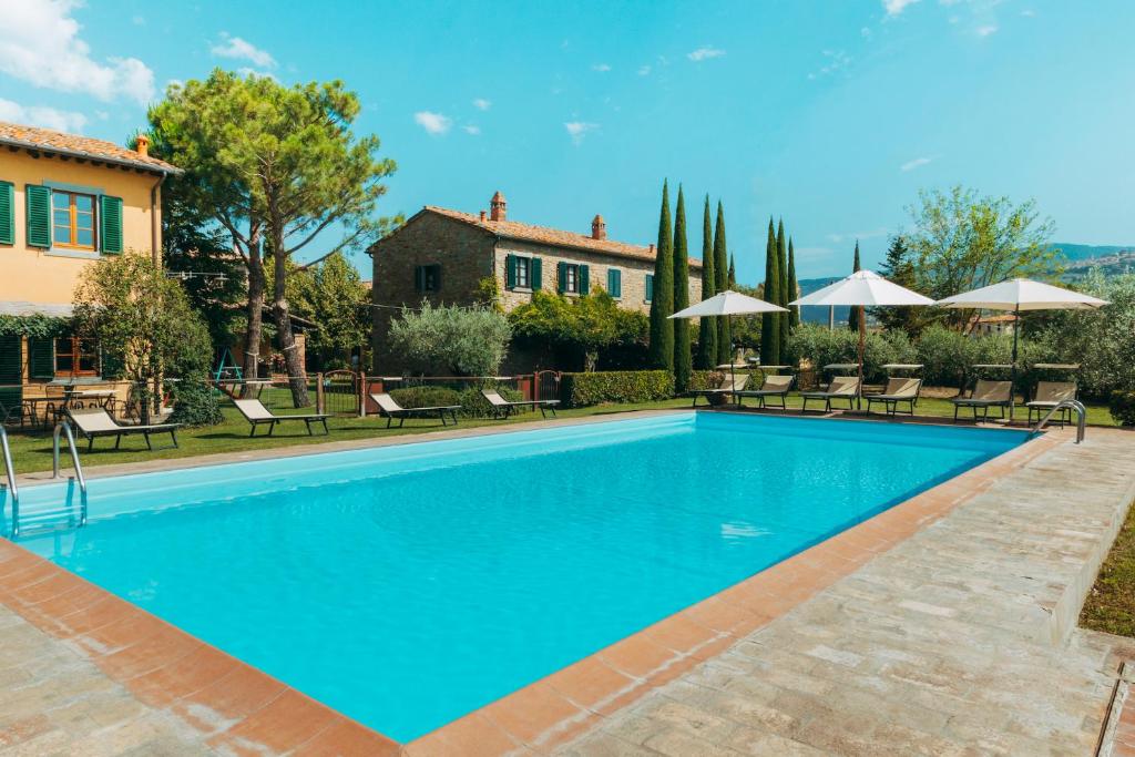 a swimming pool with chairs and umbrellas next to a house at Agriturismo Il Borgo in Cortona