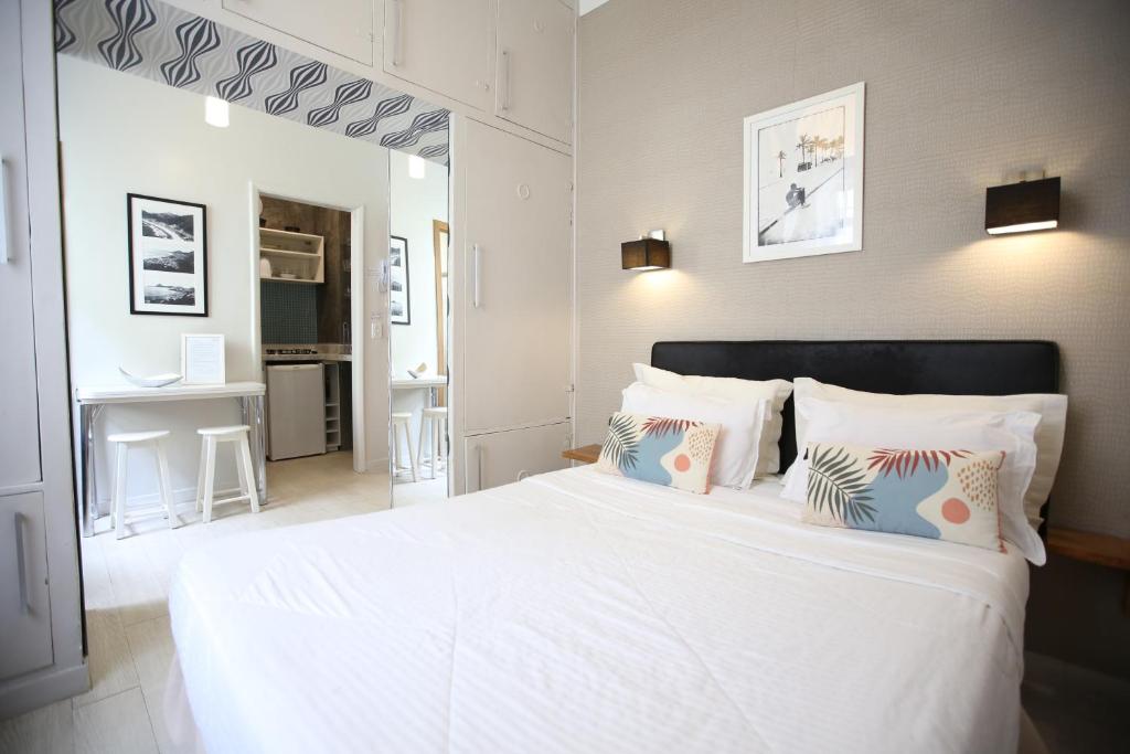 1 dormitorio con 1 cama blanca grande con almohadas en Unhotel - Charmoso Studio no Leblon, entre a Praia e Rua Dias Ferreira, en Río de Janeiro