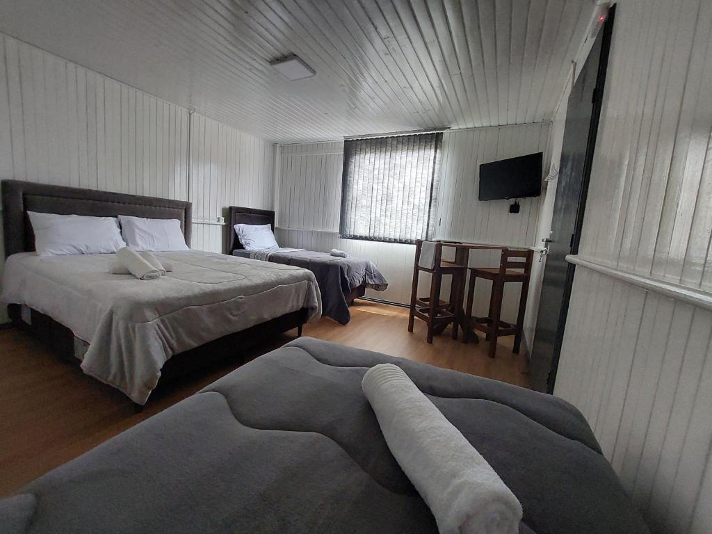 a hotel room with two beds and a television at Pousada Caminho do Altos in Bom Jardim da Serra