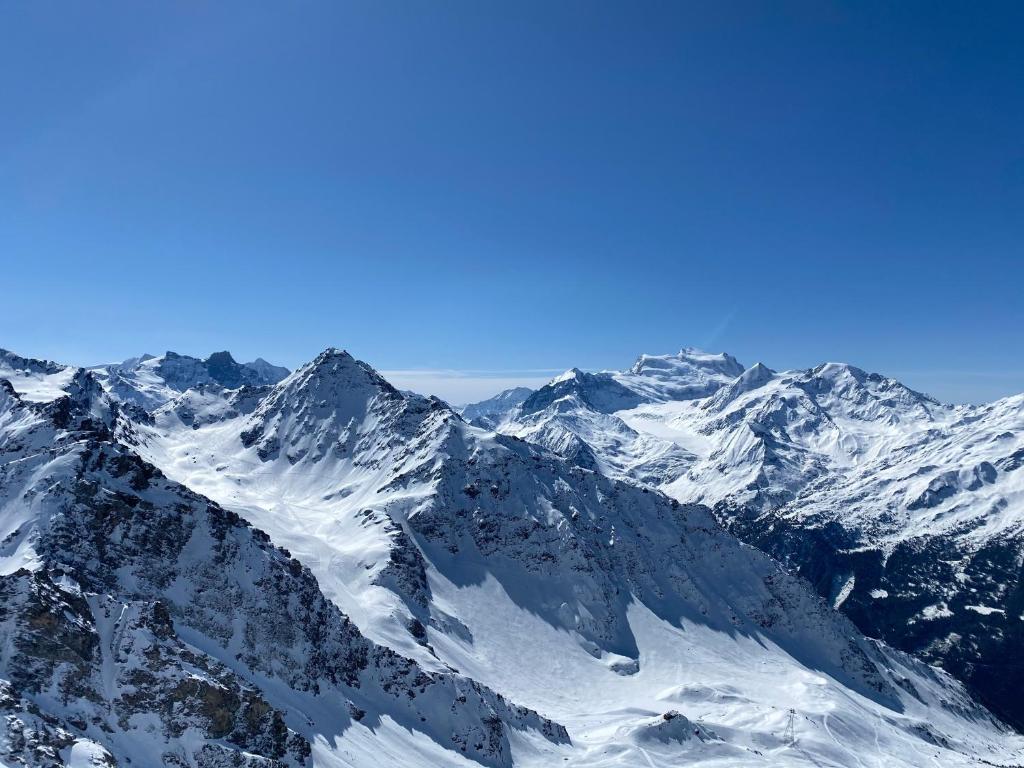 una catena montuosa ricoperta di neve con un cielo blu di Villa Fleurettes STUDIO a Le Châble