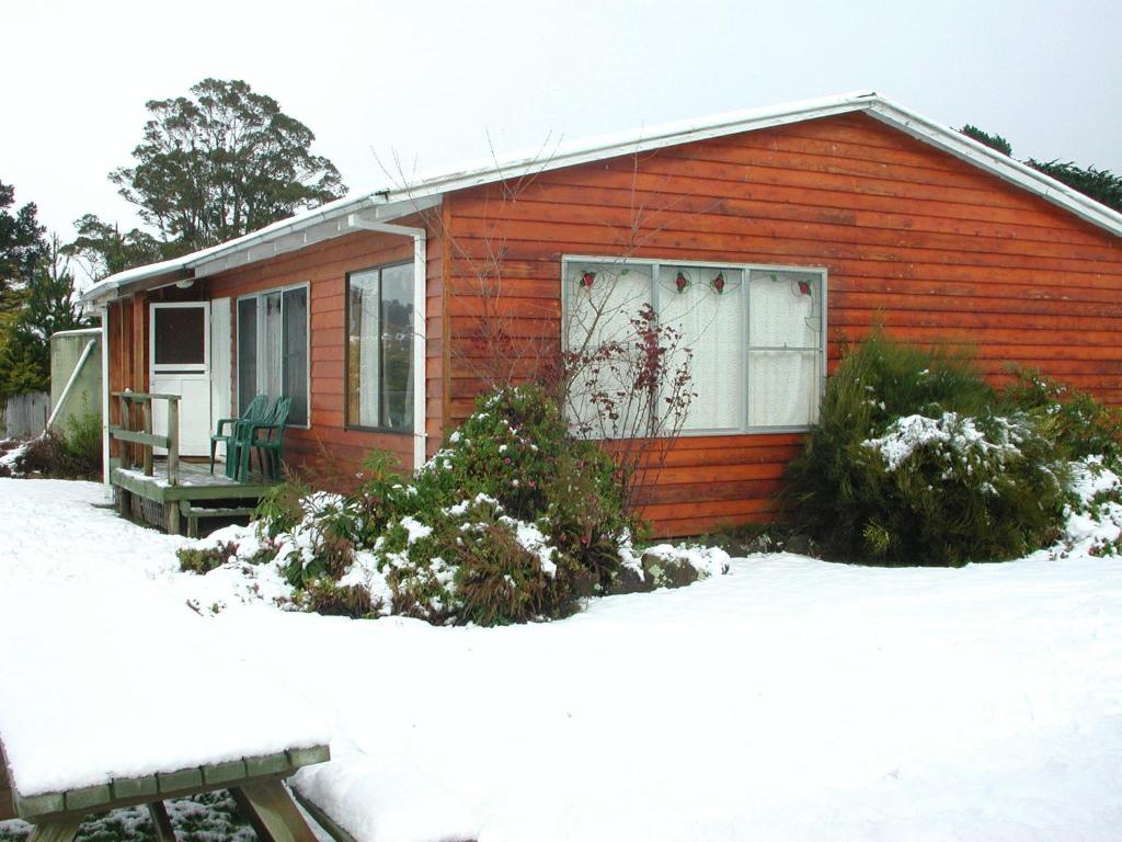 una pequeña casa roja con nieve en el suelo en AAA Granary Accommodation en Promised Land