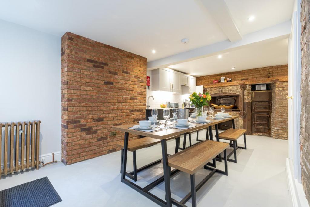 une salle à manger avec une table et un mur en briques dans l'établissement The Bakery A Renovated Gem in Central Brighton, à Brighton et Hove