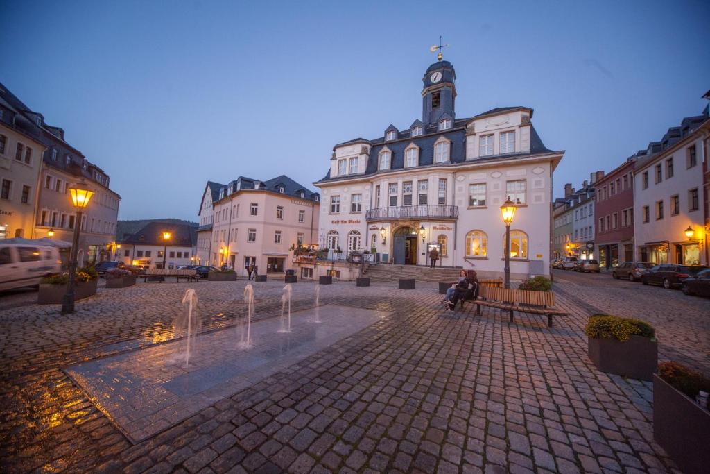 a person sitting on a bench in front of a building at Hotel Ratskeller Schwarzenberg in Schwarzenberg