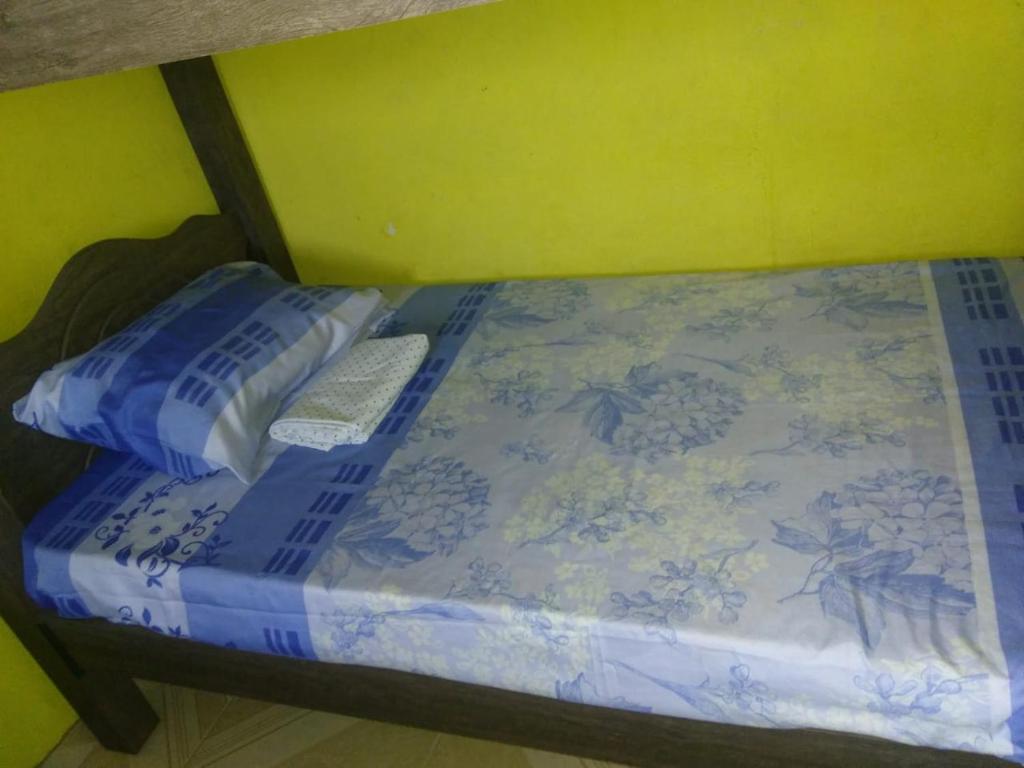 a small bed with blue and white sheets and pillows at Lençóis Hospedagens in Barreirinhas