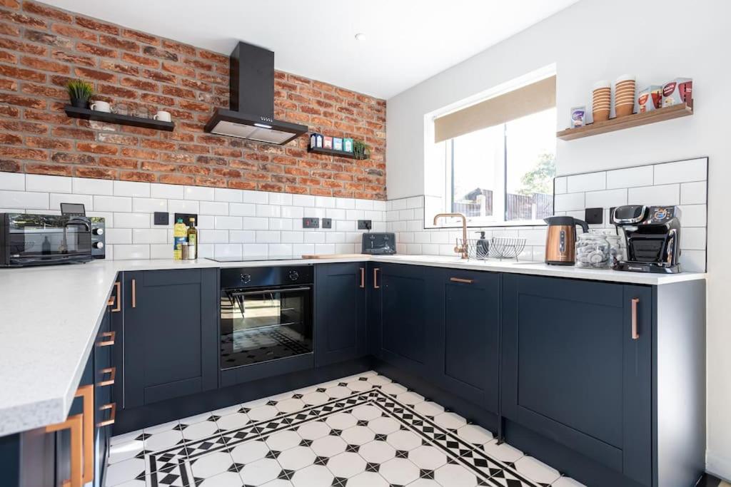 a kitchen with blue cabinets and a brick wall at Stylish Railway Themed House - Central Warrington in Warrington