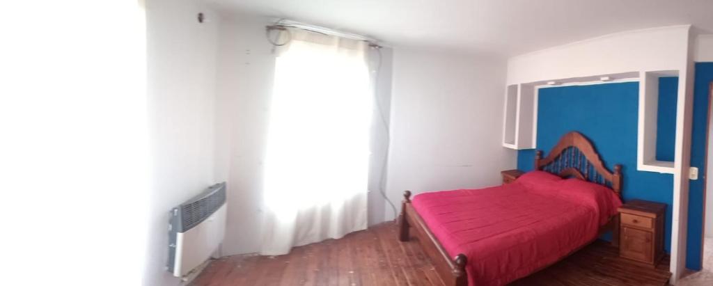 1 dormitorio con cama roja y ventana en Casa Santa Teresita en Santa Teresita