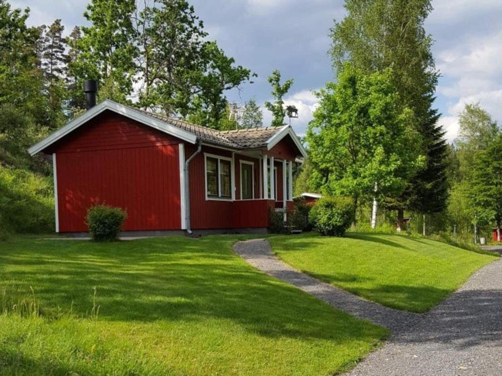 une maison rouge avec une pelouse verte devant elle dans l'établissement Holiday home Hillerstorp, à Hillerstorp