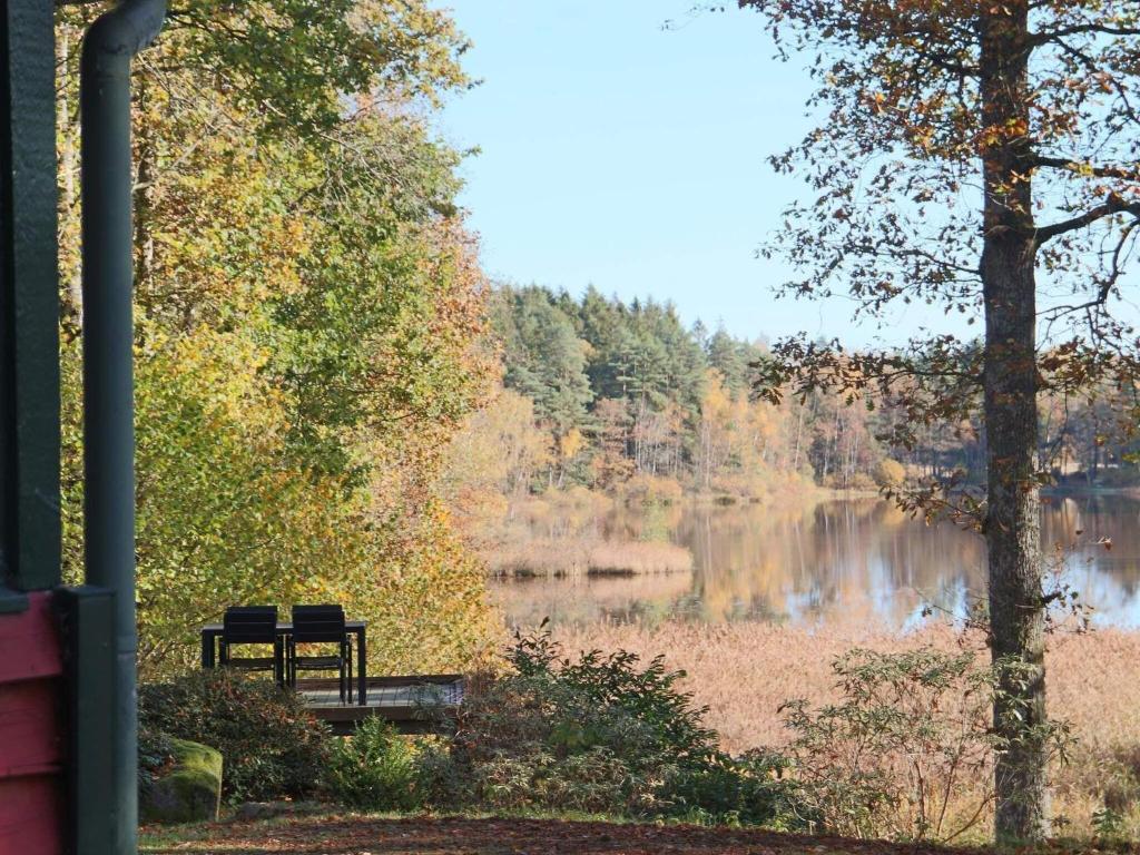 eine Parkbank neben einem See mit Bäumen in der Unterkunft 4 person holiday home in SKÅNES-FAGERHULT-By Traum in Slättsjö