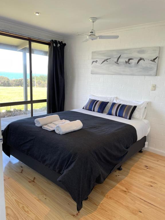 ein Schlafzimmer mit einem großen Bett mit zwei Handtüchern darauf in der Unterkunft Ocean Road Motel in Skenes Creek