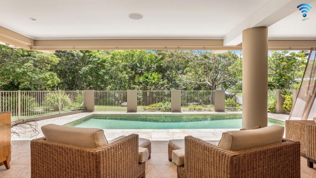 a swimming pool in a house with two chairs at Stanwell Beach Glass House in Stanwell Park