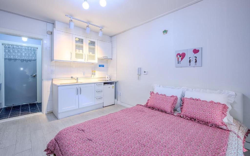 a bedroom with a pink bed and a sink at Rest Pension in Pyeongchang
