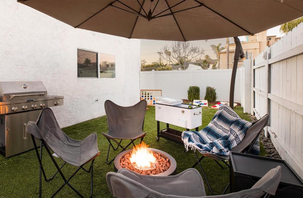 a backyard with a fire pit and chairs and an umbrella at Indigo By AvantStay Sleek Charming Home 2 Blks from Bay w Hot Tub in San Diego