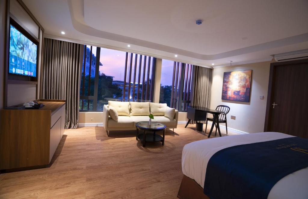 ein Hotelzimmer mit einem Bett, einem Sofa und einem TV in der Unterkunft Millennium Hue Hotel in Hue