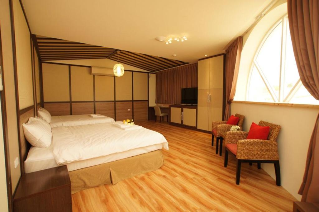 a bedroom with a bed and two chairs and a window at Taitung Venice B&B in Taitung City