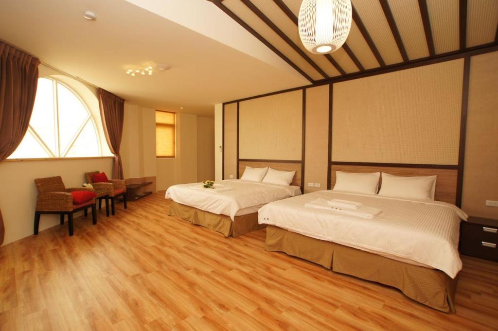 a hotel room with two beds and a table and chairs at Taitung Venice B&amp;B in Taitung City