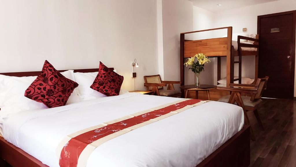a bedroom with a large white bed with red pillows at Sok Hotel And Coffee Siem Reap in Siem Reap