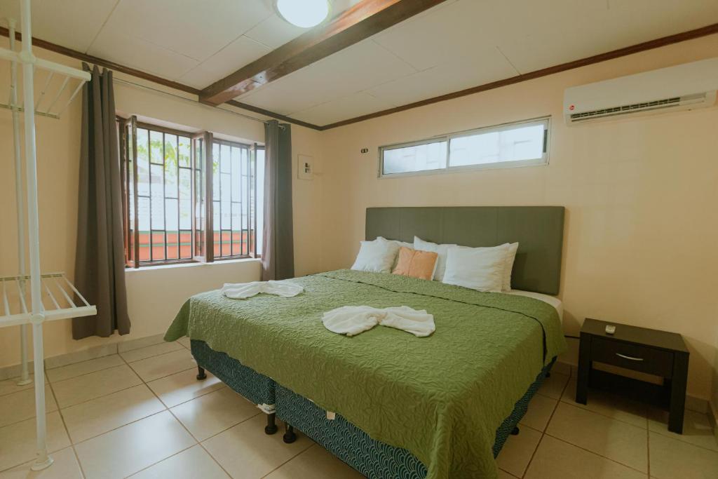 1 dormitorio con 1 cama con edredón verde en Quepos Inn, en Quepos