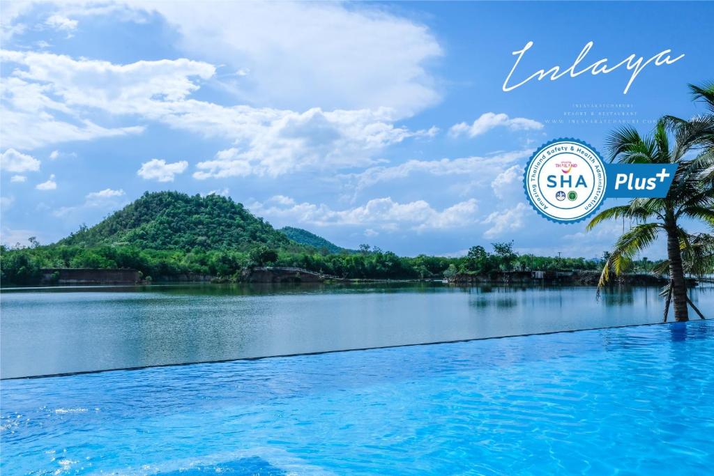 a view of a lake with palm trees and a mountain at Inlaya Ratchaburi in Ratchaburi