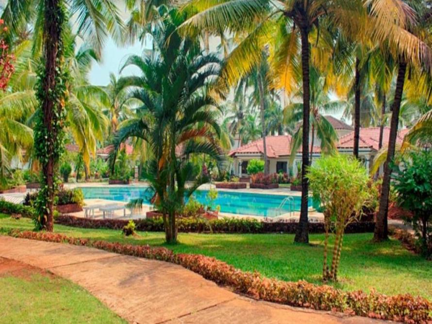 um resort com piscina e palmeiras em Villa Cavelossim em Cavelossim