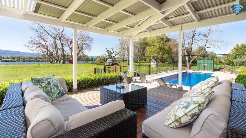 een patio met een bank, een tafel en een zwembad bij Terara Riverview Estate in Terara