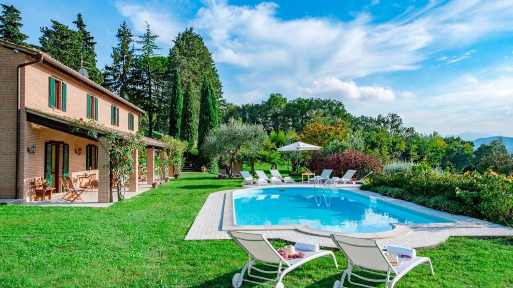 een achtertuin met een zwembad en stoelen en een huis bij VILLA IL BAIOCCO 8, Emma Villas in Ospedaletto