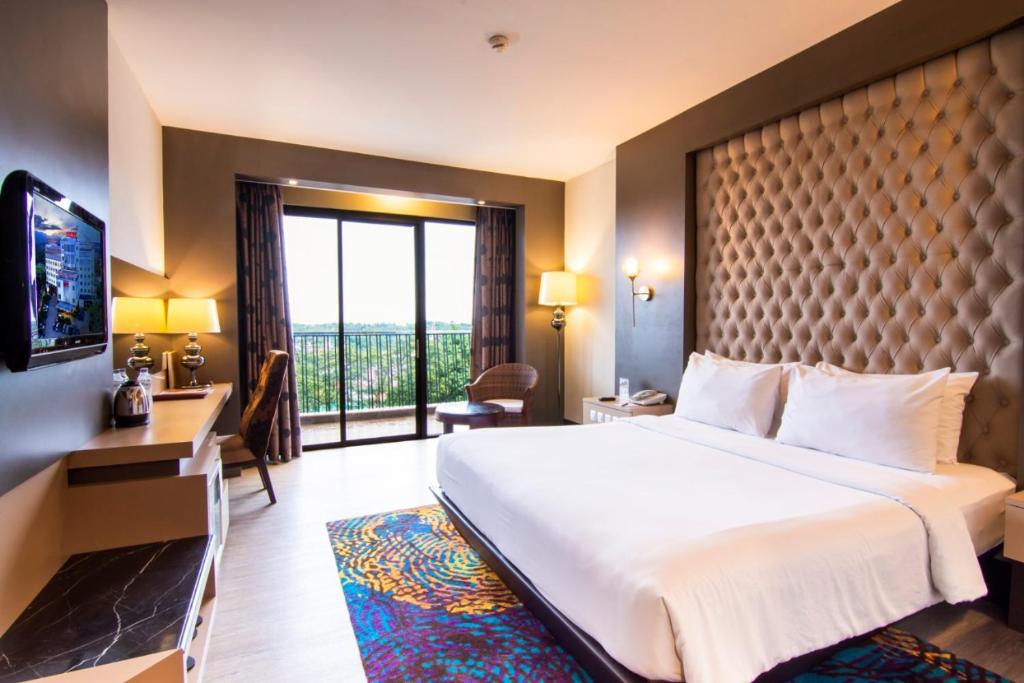 Grand Rocky Hotel Bukittinggi في بوكيتينجى: غرفة فندقية بسرير كبير ونافذة كبيرة