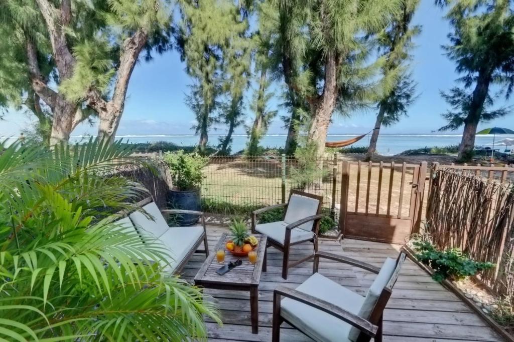 un patio con sillas y una mesa con el océano en el fondo en La villa Caroline - La Saline les Bains en La Saline les Bains