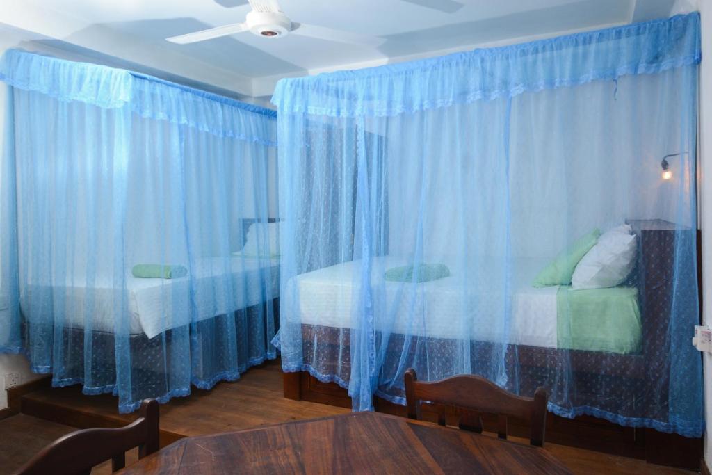 a room with two beds and blue drapes at SEVENTY SEVEN GALLE in Galle