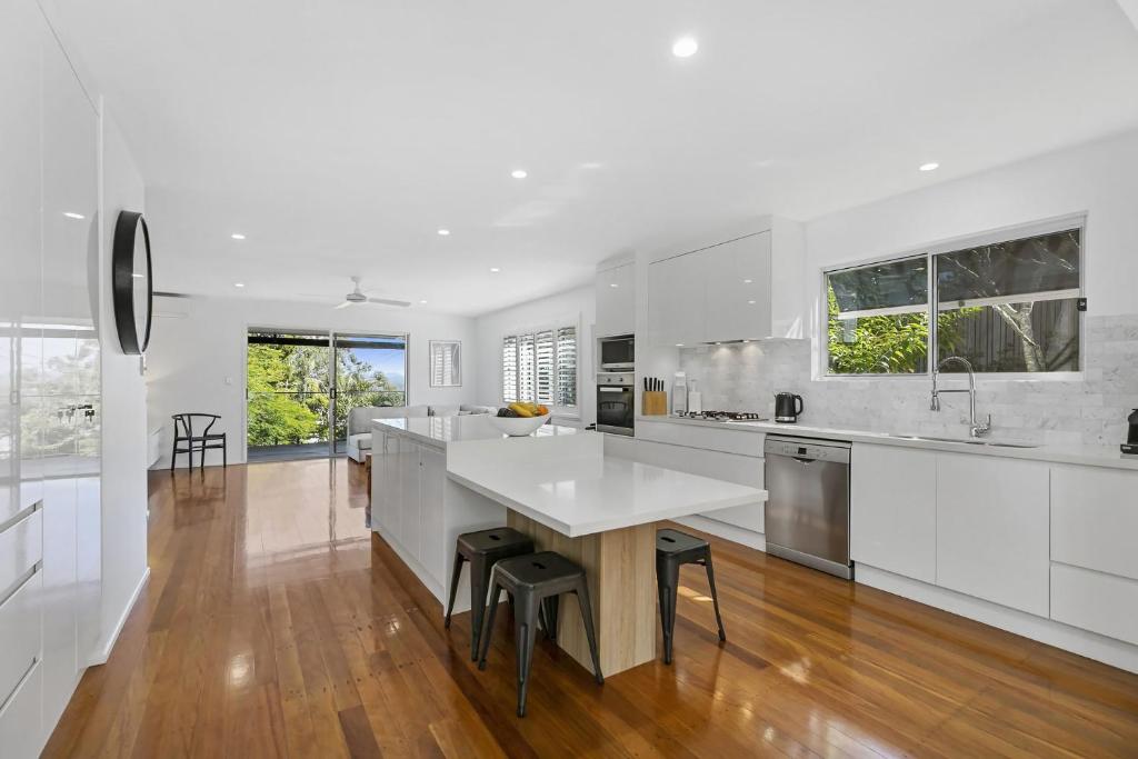 a kitchen with white cabinets and a large white island at 21 Nairana Rest Noosa Heads in Noosa Heads