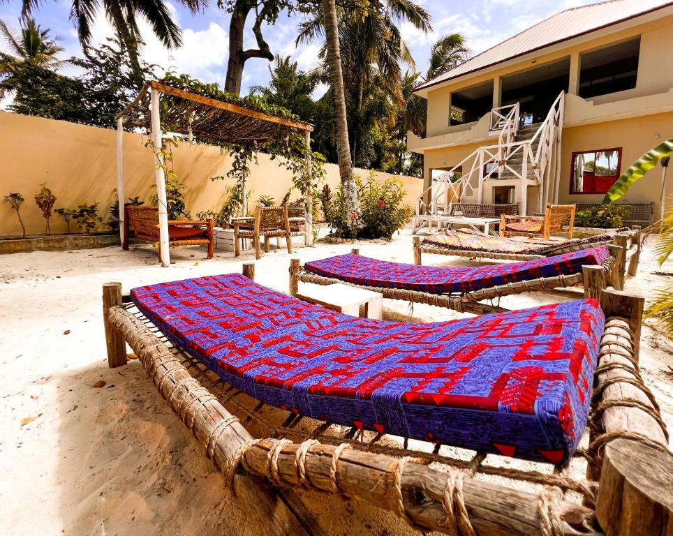 un par de camas sentadas en la arena cerca de una casa en Freshi Residence, en Jambiani