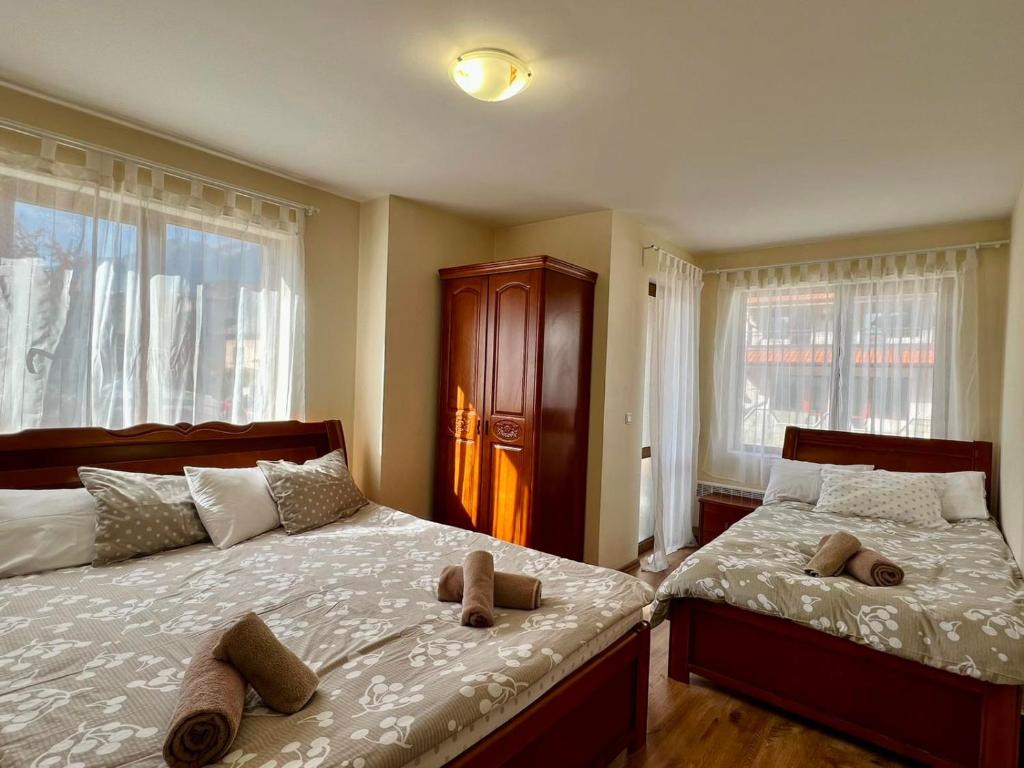 a bedroom with two beds and two windows at Prime Apartments in Bansko