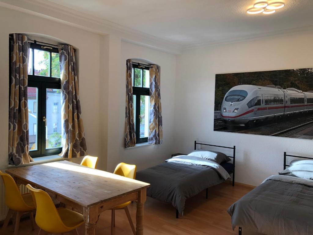 a room with two beds and a table and a train picture at Ferienwohnung Nordluft in Erfurt