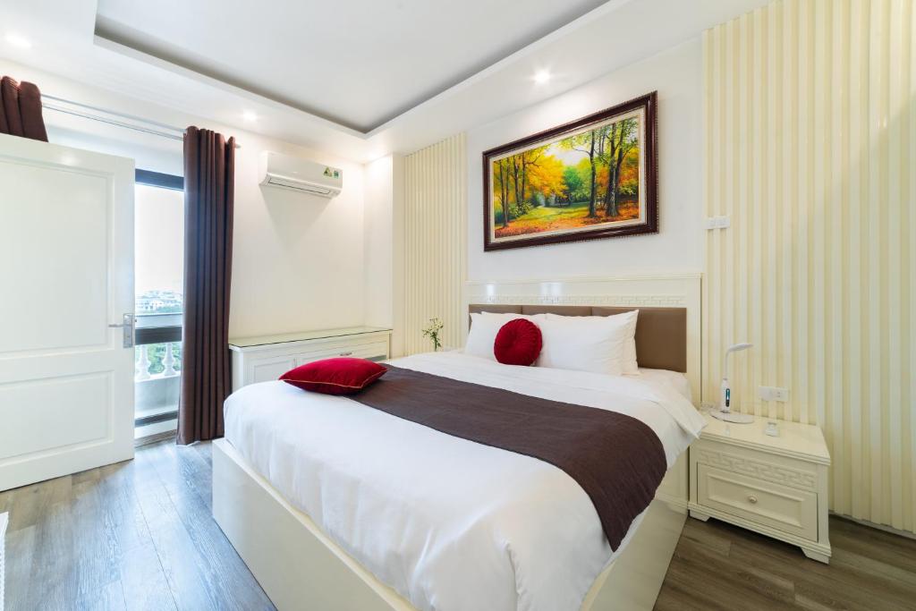 um quarto com uma grande cama branca com almofadas vermelhas em Rosee Apartment Hotel - Luxury Apartments in Cau Giay , Ha Noi em Hanói
