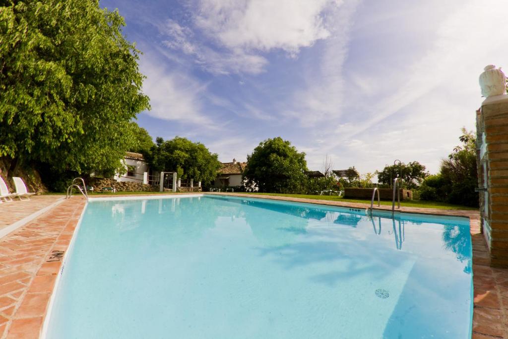 una gran piscina azul con fondo de cielo en Cortijo Balzain, en La Zubia