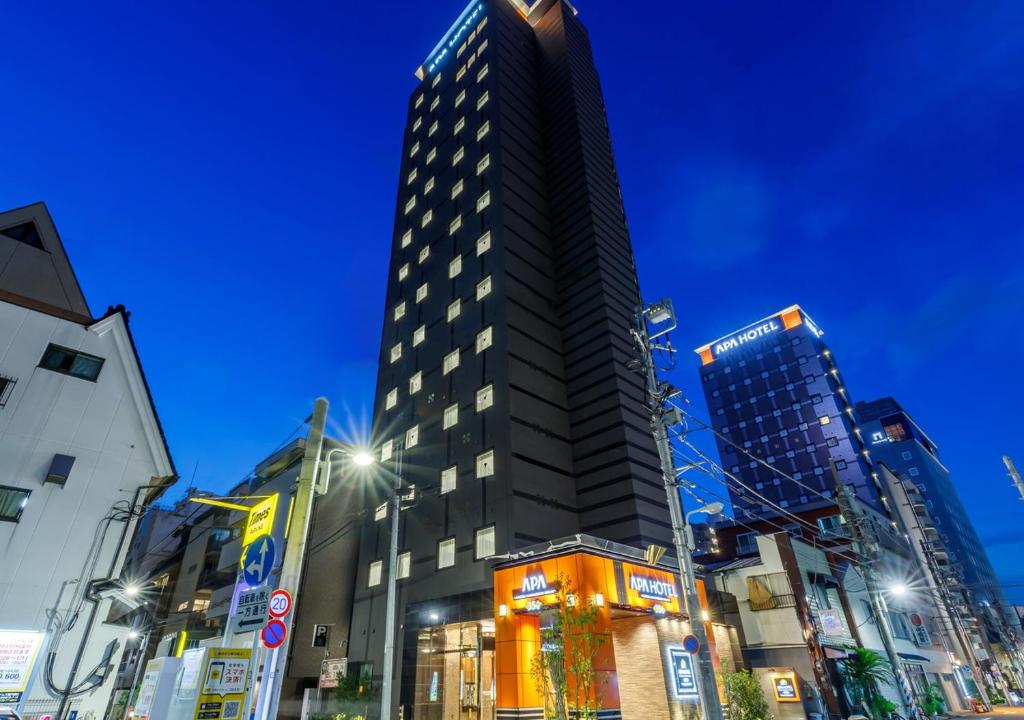 un edificio alto y negro en una ciudad por la noche en APA Hotel Asakusa Kaminarimon Minami en Tokio