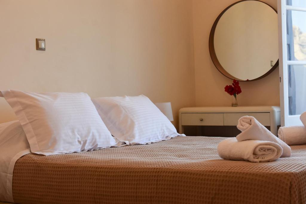 a bedroom with a bed with white pillows and a mirror at Apollonia Hotel in Masouri