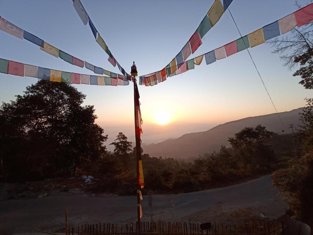 a view of the sunset through a flag pole at Dubochaur Rest house & homestay in Nagarkot