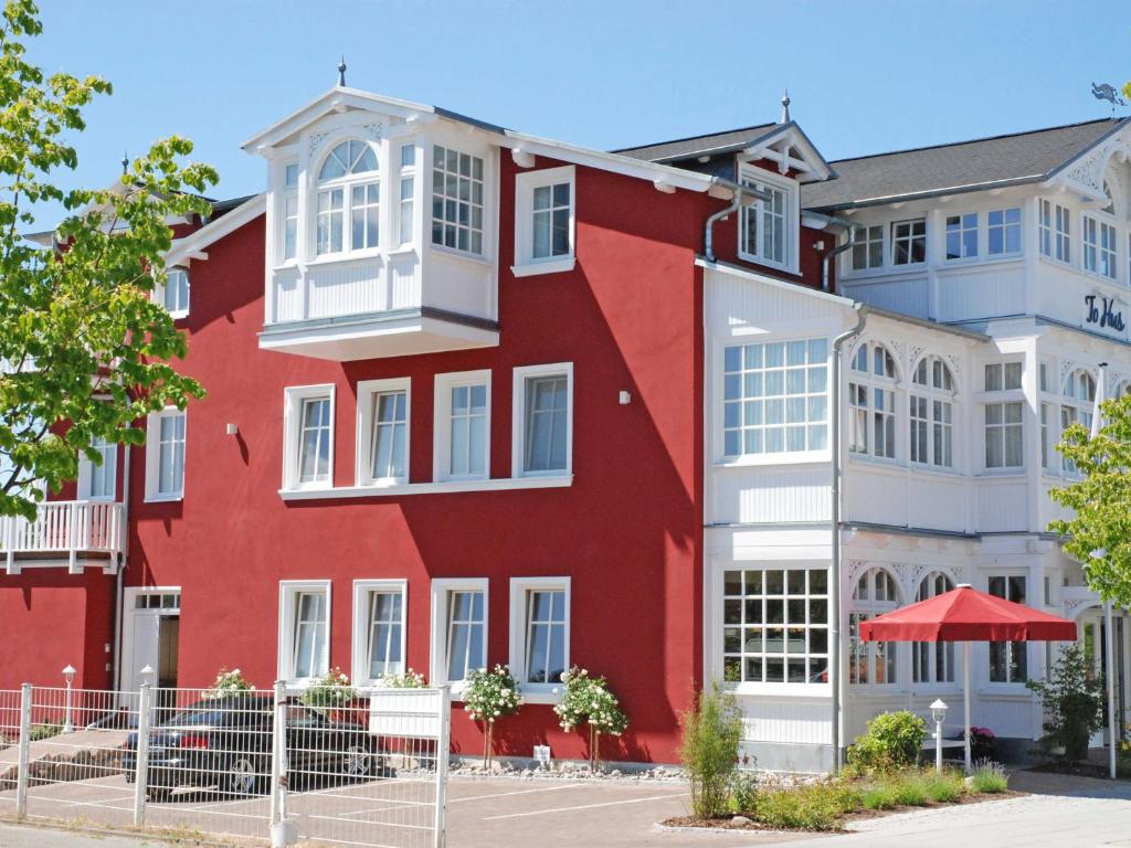un edificio rojo con ventanas blancas en Villa "To Hus" in Sellin - Appartement 05 im DG mit Kamin und Balkon, en Ostseebad Sellin