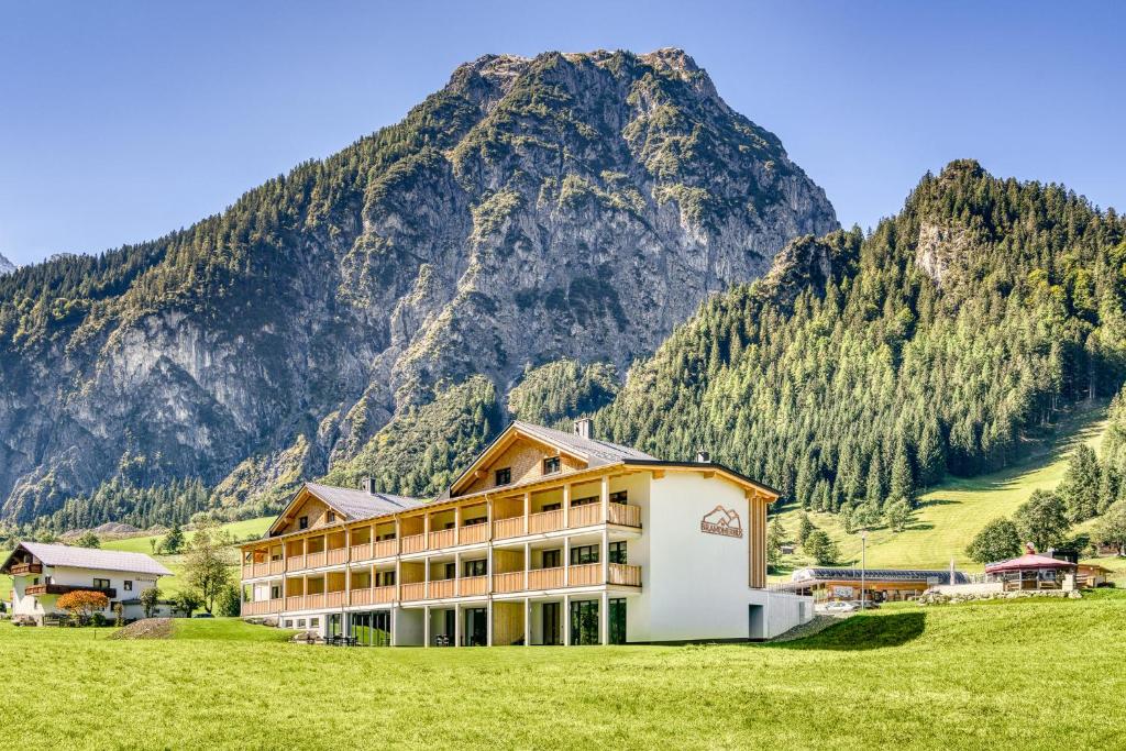 ein Gebäude auf einem Feld mit einem Berg im Hintergrund in der Unterkunft Brandnerhus by A-Appartments in Brand