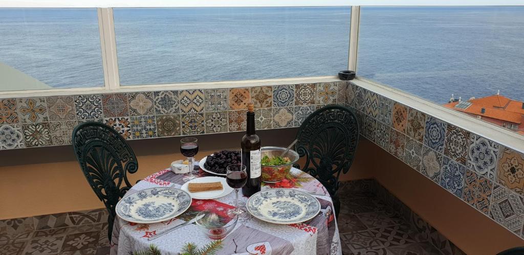 a table with food and a bottle of wine on a balcony at Apartamento Romantico by the Ocean in Caniço