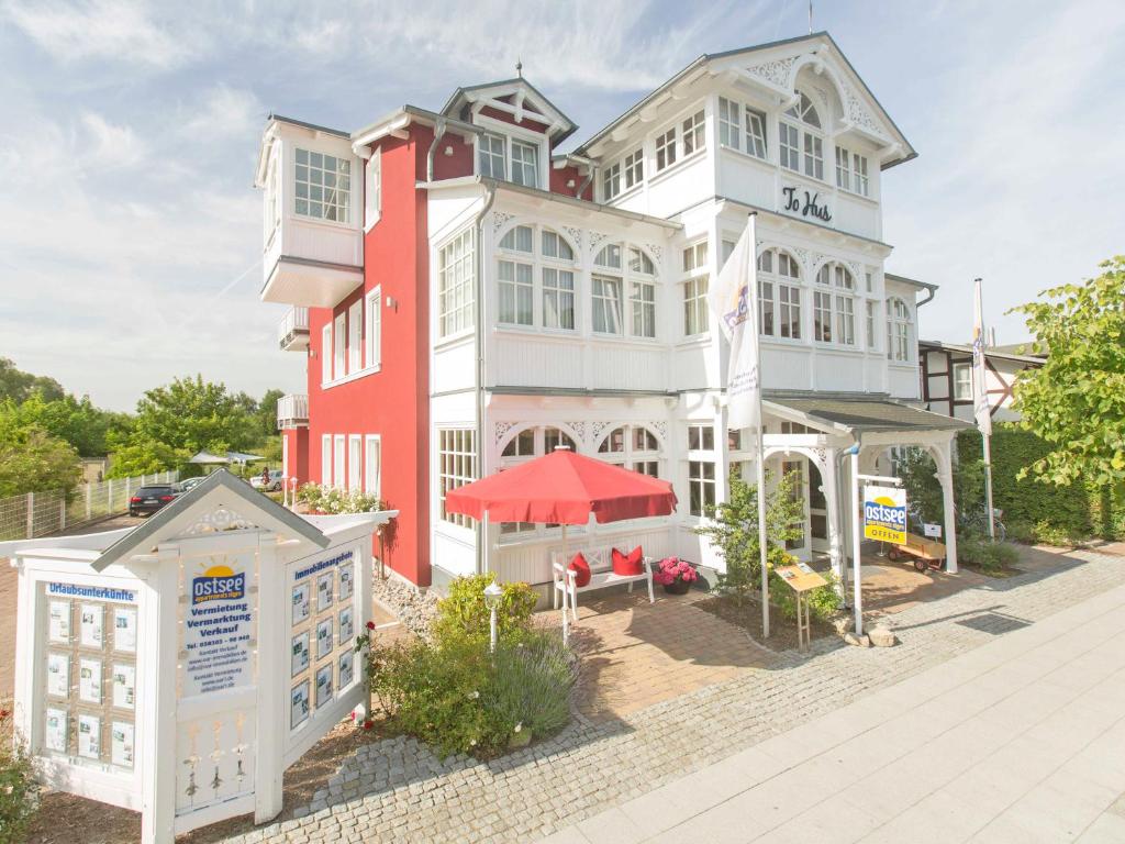 a large red and white building with a patio at Villa "To Hus" in Sellin - WG 02 mit Kamin und Balkon in Ostseebad Sellin